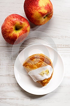 Piece of cinnamon apple pie on a white plate with fresh apple in background, autumn food concept