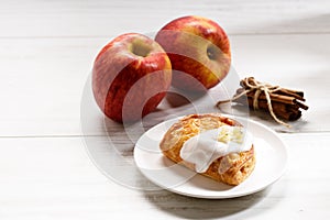 Piece of cinnamon apple pie on a white plate with fresh apple in background, autumn food concept