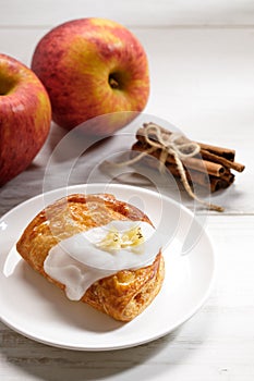 Piece of cinnamon apple pie on a white plate with fresh apple in background, autumn food concept
