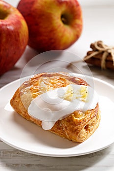 Piece of cinnamon apple pie on a white plate with fresh apple in background, autumn food concept