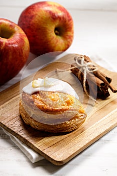 Piece of cinnamon apple pie on a wooden board with fresh apple in background, autumn food concept