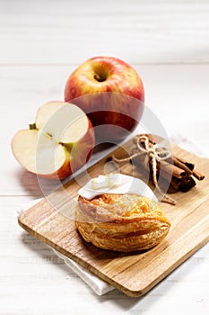 Piece of cinnamon apple pie on a wooden board with fresh apple in background, autumn food concept