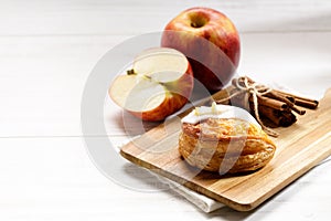 Piece of cinnamon apple pie on a wooden board with fresh apple in background, autumn food concept