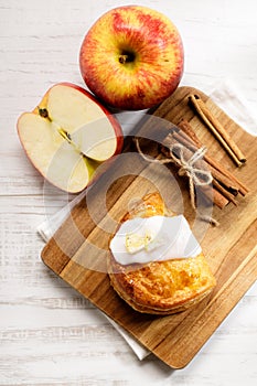 Piece of cinnamon apple pie on a wooden board with fresh apple in background, autumn food concept