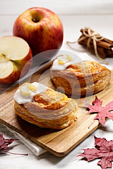 Piece of cinnamon apple pie on a wooden board with fresh apple in background, autumn food concept