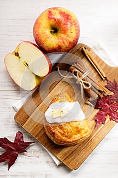 Piece of cinnamon apple pie on a wooden board with fresh apple in background, autumn food concept