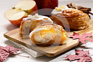 Piece of cinnamon apple pie on a wooden board with fresh apple in background, autumn food concept