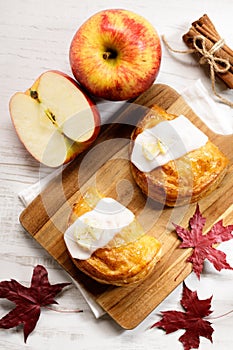 Piece of cinnamon apple pie on a wooden board with fresh apple in background, autumn food concept