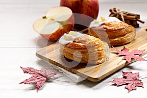 Piece of cinnamon apple pie on a wooden board with fresh apple in background, autumn food concept