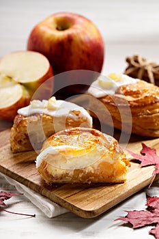 Piece of cinnamon apple pie on a wooden board with fresh apple in background, autumn food concept