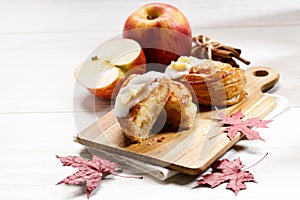 Piece of cinnamon apple pie on a wooden board with fresh apple in background, autumn food concept