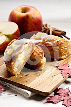 Piece of cinnamon apple pie on a wooden board with fresh apple in background, autumn food concept