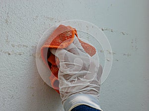 A piece of cloth, soaked with thinner, in a hand of a painter being used to remove sticky rough glue and tape remain on the old photo