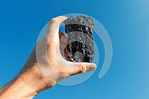 Piece of coal in a hand raised to the sky