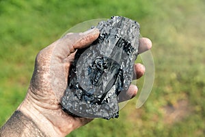 Piece of coal in a miner's dirty hand. Energy and fuel industry