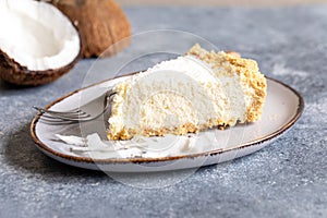 Piece of coconut cheesecake on a plate with fresh coconut