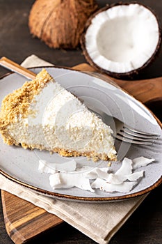 Piece of coconut cheesecake on a plate with fresh coconut