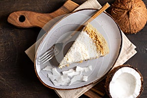 Piece of coconut cheesecake on a plate with fresh coconut