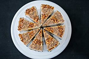 Piece of Coffee almond caramel cake on white plate in coffee shop on black background