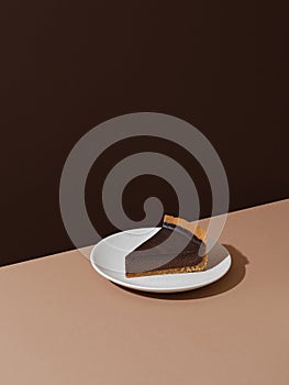 Piece of d?rk chocolate cheesecake on beige and brown background