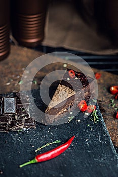 Piece of dark chocolate cake with red hot pepper. The restaurant or cafe atmosphere. Retro. Vintage