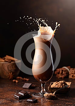 Piece of dark chocolate fall into a glass of cocoa drink