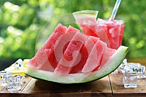 A piece of decoratively sliced watermelon and drink on the table in the garden