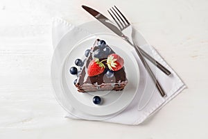 Piece of delicious chocolate cake with berries on plate