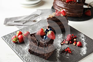 Piece of delicious chocolate cake with berries on slate plate