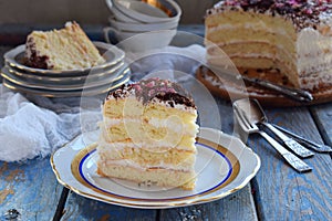 A piece of delicious coconut layer cake - a biscuit and cream on coconut cream, decorated with grated chocolate and candied rose