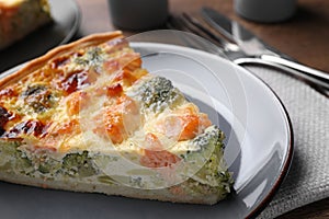 Piece of delicious homemade quiche with salmon and broccoli on plate, closeup