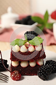 Piece of delicious red velvet cake with fresh berries on plate, closeup