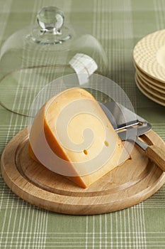 Piece of Dutch Gouda cheese on a wooden board