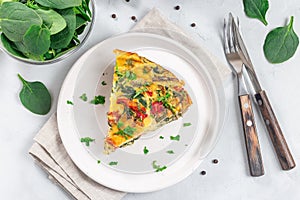 Piece of egg frittata with spinach, roasted peppers, mushrooms, cheese, horizontal, top view