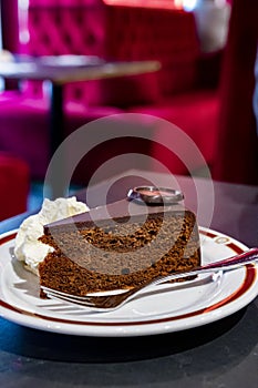 Piece of famous Sachertorte chocolate cake with apricot jam of Austrian origin served with whipped cream