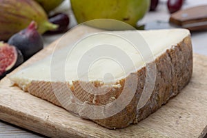 Piece of French cheese Tomme de Brebis made from sheep milk served as dessert with fresh figs and pears