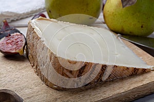 Piece of French cheese Tomme de Brebis made from sheep milk served as dessert with fresh figs and pears