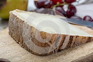 Piece of French cheese Tomme de Brebis made from sheep milk served as dessert with fresh figs and pears