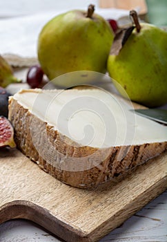 Piece of French cheese Tomme de Brebis made from sheep milk served as dessert with fresh figs and pears