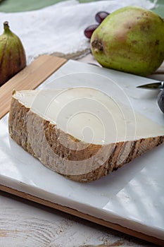 Piece of French cheese Tomme de Brebis made from sheep milk served as dessert with fresh figs and pears