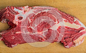 A piece of fresh beef with bone and fat lies on the cutting board