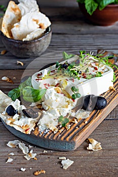 A piece of fresh feta cheese paneer with olives, herbs, spices and slices of flatbread tortilla, lavash, pitta, chapatti