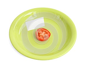 Piece of a fresh tomato with blank cardboard information tag on a green plate