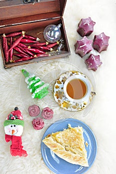 Piece of greek feta cheese pie, tea and Christmas ornaments