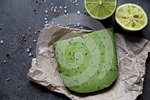 Piece of green cheese on crushed paper with lime