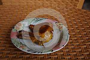 A piece of grilled chicken thigh and chicken thigh on a small plate with a floral pattern that looks perfectly cooked