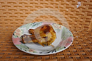 A piece of grilled chicken thigh and chicken thigh on a small plate with a floral pattern that looks perfectly cooked