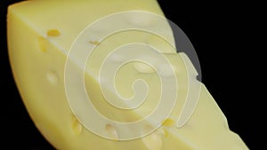 Piece of hard cheese rotating in a circle, black background, and space for text.