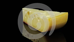 Piece of hard cheese rotating in a circle, black background, and space for text.