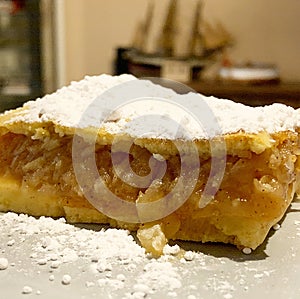 A piece of home-made cake, apple pie, a cake with lots of fruit, a dessert sprinkled with powdered sugar, sweets